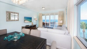 A spacious living area with a view of the ocean, a dining table with a decorative glass bowl, and a comfortable seating arrangement.