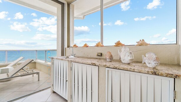 Un balcon avec vue sur la mer, une armoire blanche et des coquillages décoratifs.