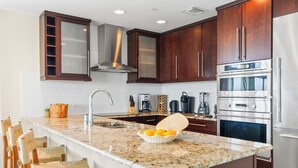 Une cuisine moderne dotée de plans de travail en granit, d’appareils électroménagers en acier inoxydable et de meubles en bois.