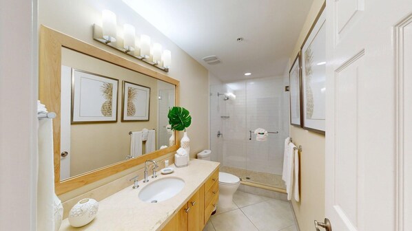 A modern bathroom with a large mirror, a sink, a toilet, and a shower area.