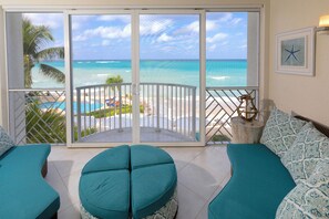 Un balcon avec vue sur l’océan et la plage, agrémenté de coussins turquoise et d’une décoration en forme d’étoile de mer.