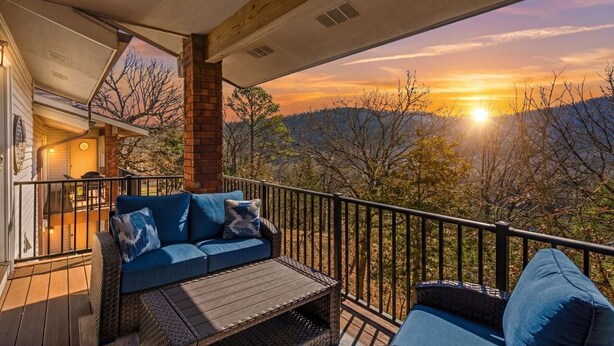 A covered outdoor seating area with a view of the sunset over a mountainous landscape. - Branson Escape ~ Pointe Royale Resort Condo ~ Pet Friendly ~ Sleeps 6 (Branson)