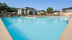 A swimming pool with lounge chairs and umbrellas, surrounded by buildings and trees. - Branson Escape ~ Pointe Royale Resort Condo ~ Pet Friendly ~ Sleeps 6 (Branson)