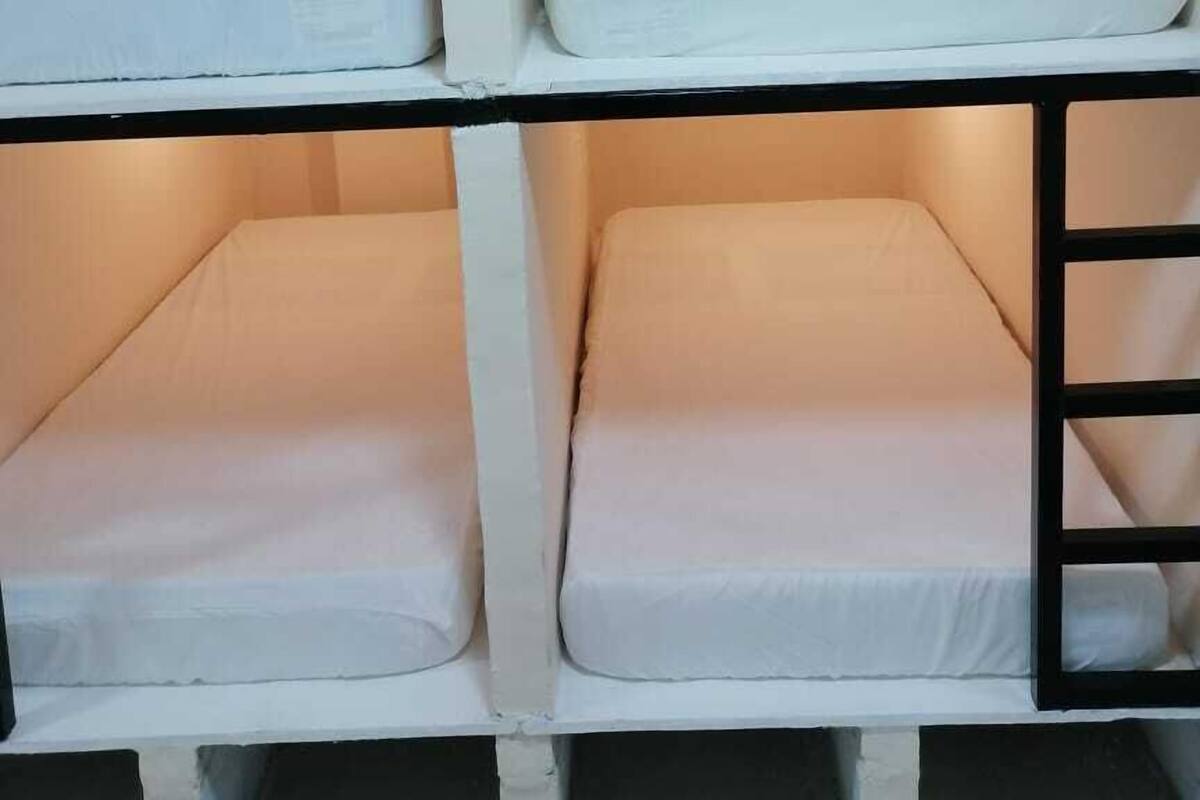 Uma cama beliche com dois níveis, cada um com um colchão e um travesseiro.