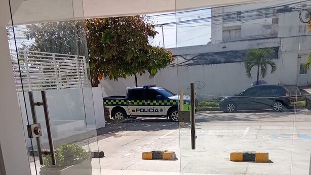 A glass door leading to a parking area with a police car parked outside.