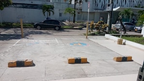 A parking area with marked spaces, a no parking sign, and a building in the background.