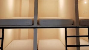 A bunk bed room with two levels, each with a mattress and a headboard.