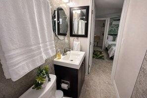 A bathroom with a toilet, sink, mirror, and towel rack.