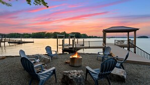 A lakeside deck with Adirondack chairs, a fire pit, and a gazebo. - Beautiful 5 Bedroom Lake-Front Home with Heated Saltwater Pool, Spa, and Dock (Denver)