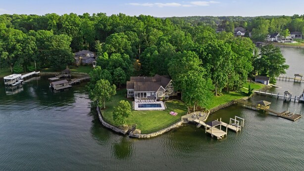 An aerial view of a lakeside property with a house, dock, and boat. - Beautiful 5 Bedroom Lake-Front Home with Heated Saltwater Pool, Spa, and Dock (Denver)