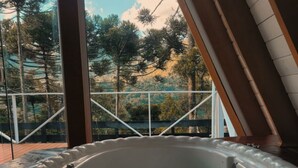 A hot tub with a view of trees through large windows. - Chalet in the middle of the icy mountains of Urubici- (Urubici)