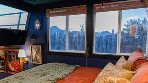 A room with a bed, two windows with a view of mountains, a television, and wall decorations. - Romantic Houseboat with out of this World Star Gazing (Alpine)