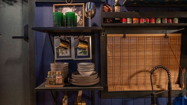 A kitchen with a blue wall, shelves with kitchenware, a framed picture, and a bamboo blind. - Romantic Houseboat with out of this World Star Gazing (Alpine)