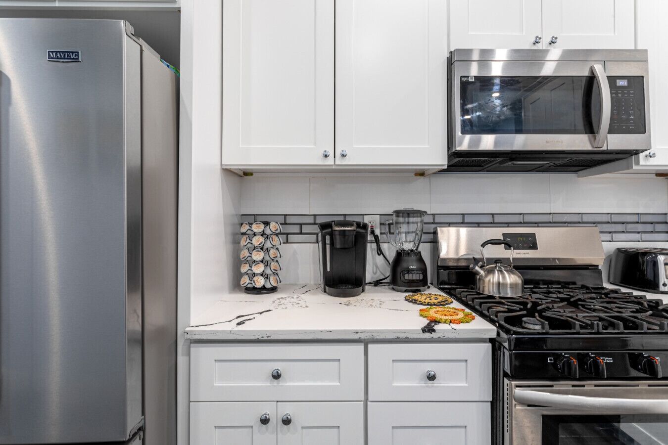 Una cocina moderna con electrodomésticos de acero inoxidable, incluyendo un refrigerador, microondas y estufa.