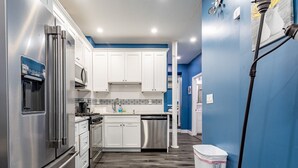 A compact kitchen with white cabinets, a stainless steel refrigerator, a dishwasher, and a microwave.