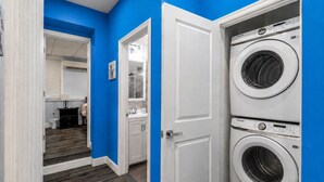 A laundry room with two stacked washers and dryers, a white door, and a blue wall.