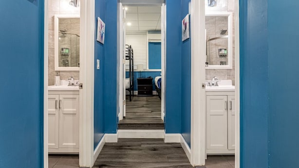 A hallway with a blue wall, white cabinets, and a gray carpet.