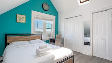 A bedroom with a bed, a window, a chair, a desk, and a wardrobe.