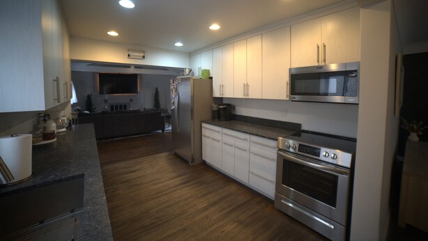 A modern kitchen with stainless steel appliances, wooden flooring, and white cabinetry. - CHARMING HOUSE ON THE NAUTICAL MILE (St. Clair Shores)