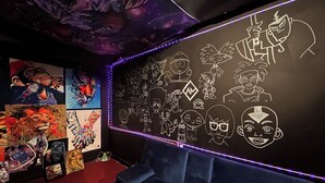 A room with a black wall featuring white cartoon character drawings, a red carpet, and a blue couch. - CHARMING HOUSE ON THE NAUTICAL MILE (St. Clair Shores)