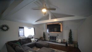 A living room with a sectional sofa, a fireplace, and a ceiling fan. - CHARMING HOUSE ON THE NAUTICAL MILE (St. Clair Shores)