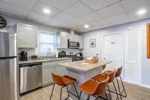A modern kitchen with stainless steel appliances, a granite countertop, and a bar area with stools.