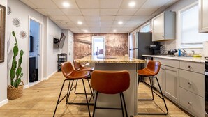 Une cuisine moderne dotée d’un îlot central, de tabourets de bar et d’une grande fenêtre.