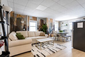 Una sala moderna con sofá, mesa de centro y un mural con vista a la ciudad.