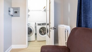 Une buanderie équipée de deux machines à laver, une porte donnant sur une autre pièce et un porte-serviettes sur lequel est posée une serviette blanche.