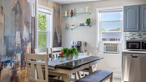 Une cuisine équipée d’une table à manger, de chaises, d’un four à micro-ondes, d’un four traditionnel et d’une étagère en verre où sont exposés des objets décoratifs.