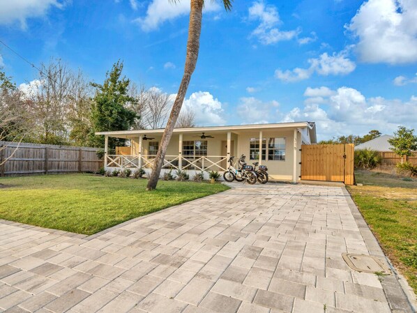 A house with a paved patio, a wooden fence, and a garage. - Pet Friendly! Close to Beach! Bikes! Fenced in Yard! (Panama City Beach)