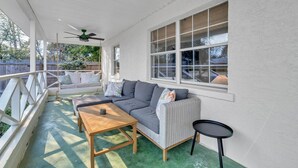 Une terrasse couverte avec un canapé gris, une table en bois et une petite table ronde.
