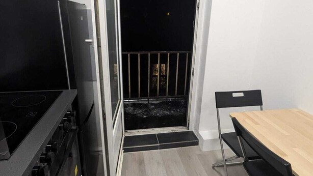 Una cucina compatta con un piano cottura nero, un tavolo da pranzo in legno e una sedia nera.