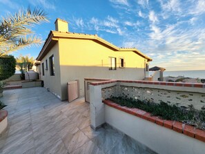 Situated on a coastal terrace, this building features a brick and stucco exterior with a prominent chimney.
