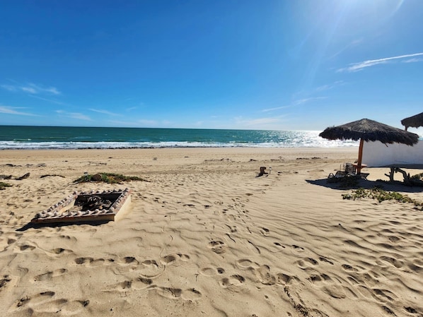 Relax on the beach with a thatched umbrella and lounge chair at hand.