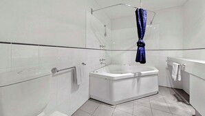 A modern bathroom with a large bathtub, a glass shower enclosure, and white tiled walls. - White Crystal 209- ski-in ski-out (Mount Hotham)