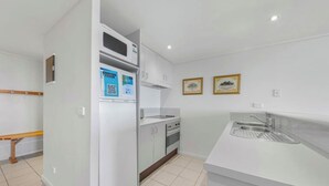 A modern kitchen with white cabinets, a built-in microwave, and a stainless steel sink. - White Crystal 209- ski-in ski-out (Mount Hotham)