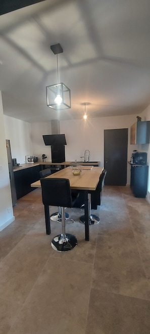 A modern kitchen with a dining table, chairs, and a hanging light fixture.