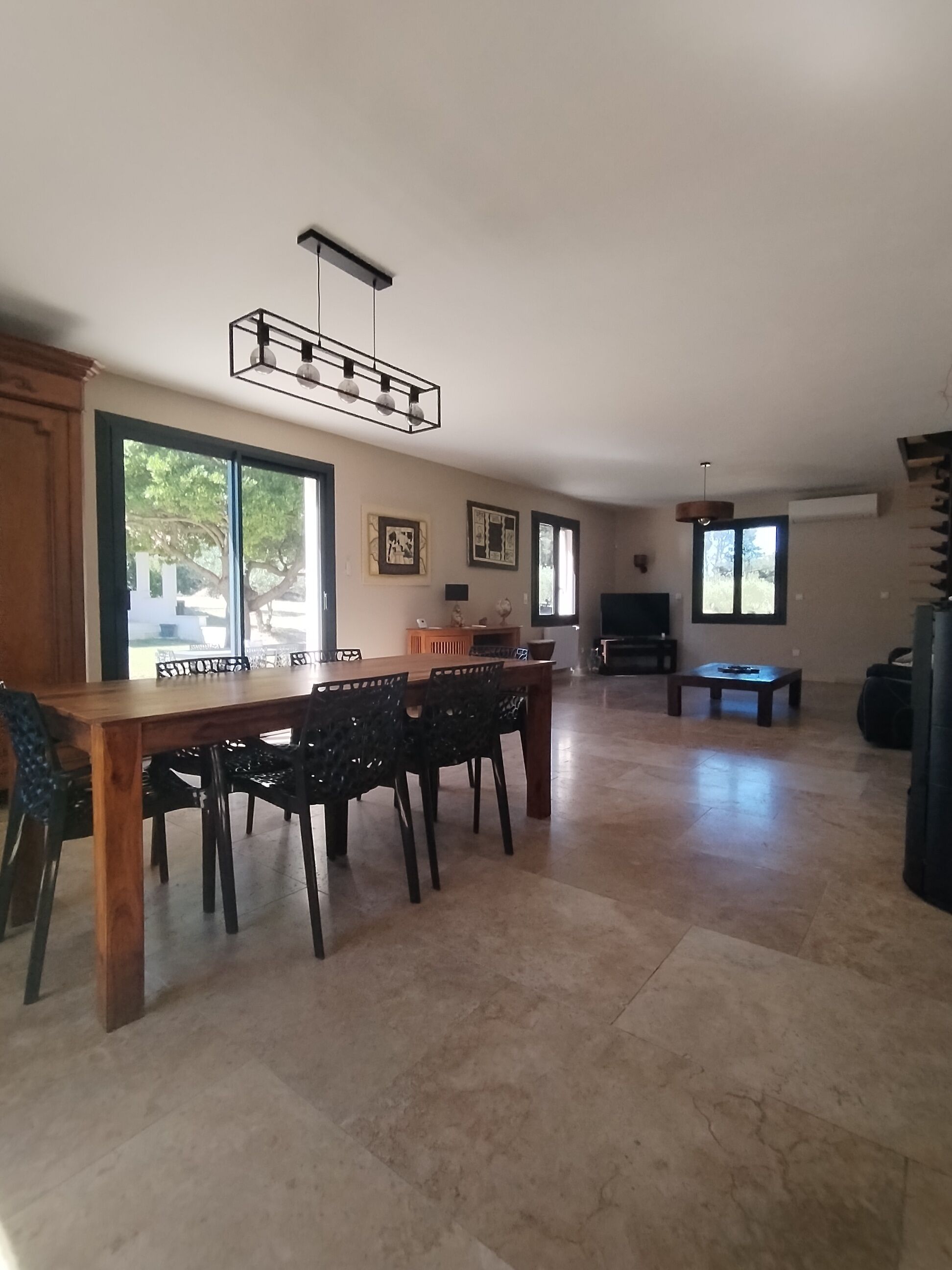 Uma sala de estar ampla com área de jantar, janelas grandes e lareira.