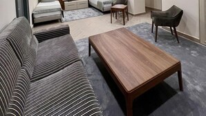 Un salon moderne avec un canapé, une table basse en bois et un coin salon comprenant un divan et des fauteuils.