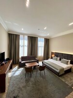 Een moderne hotelkamer met een groot bed, een bank, een bureau en een televisie.