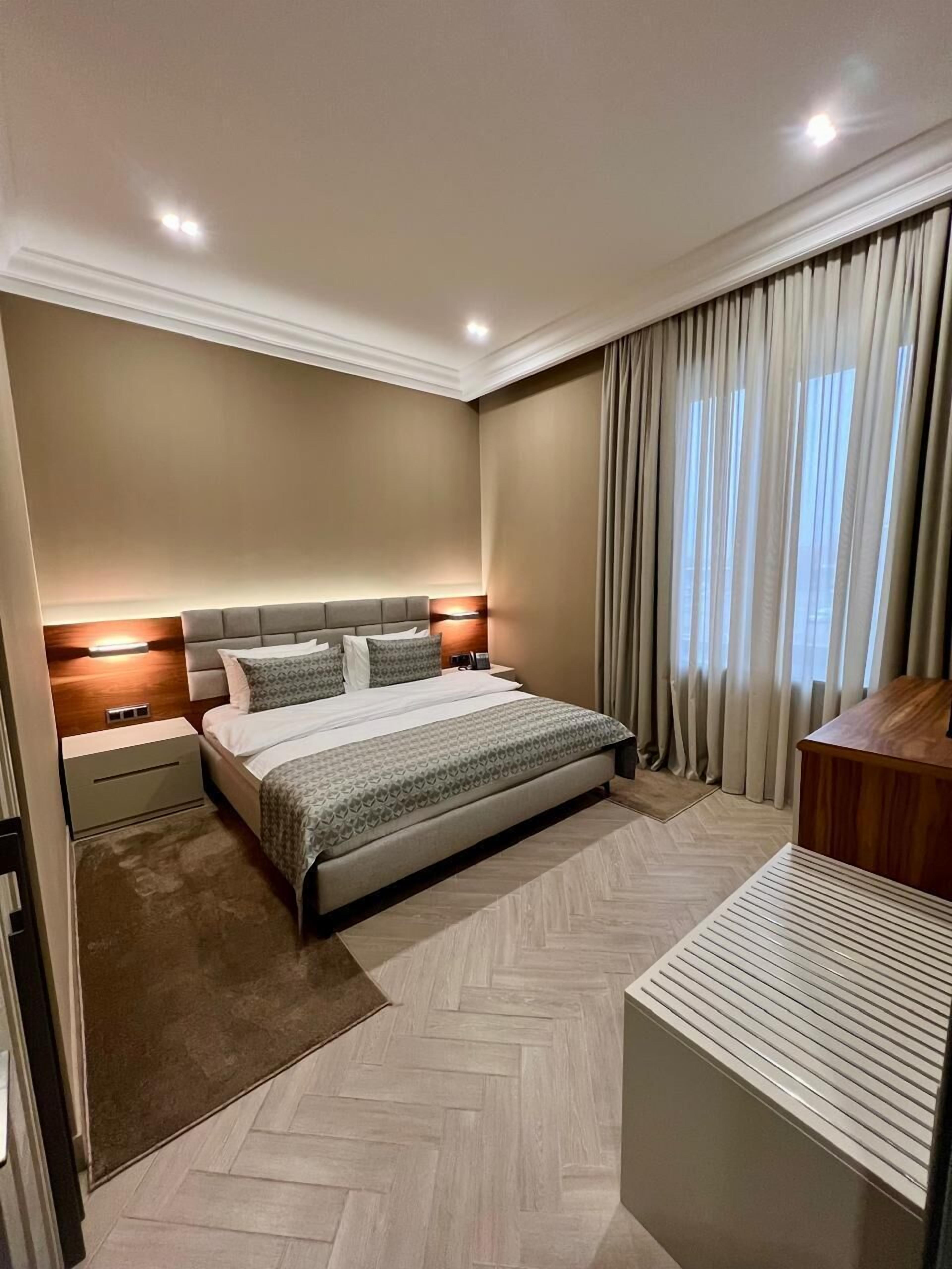Una habitación de hotel moderna con una cama grande, un escritorio y vistas al exterior por la ventana.