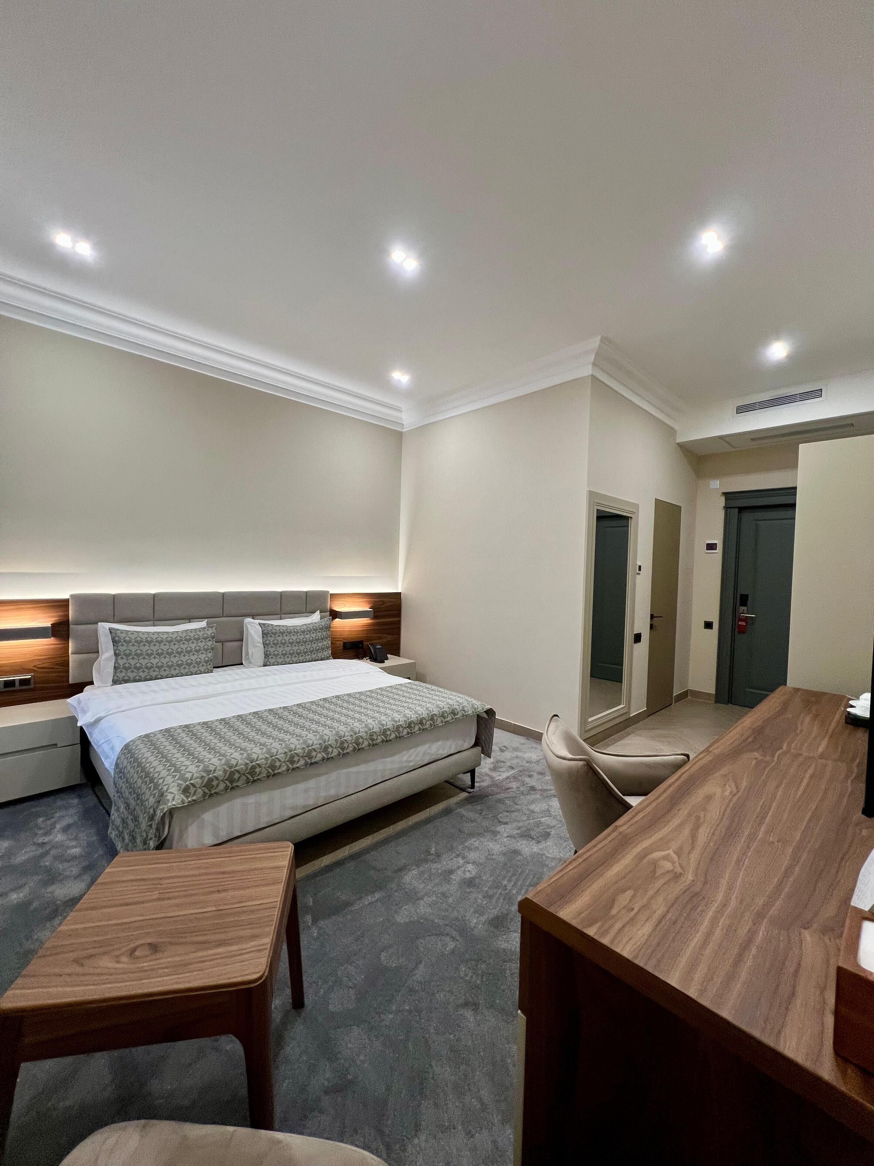 Una habitación de hotel con una cama grande, mesitas de noche, un escritorio y una silla.