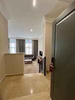 Een hotelkamer met een bank, televisie en uitzicht op de stad.