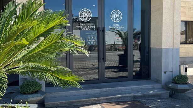 L’entrée de l’hôtel Plaza Viktoria à Erevan se distingue par son design moderne, avec de grandes portes vitrées et une façade en pierre.