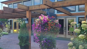 Un bâtiment moderne doté de grandes fenêtres et d’un espace extérieur abrité agrémenté de jardinières suspendues.
