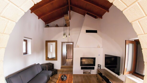 A living room with a sofa, a coffee table, a TV, and a fireplace. - Anasa Residence (Chania)