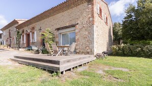 A rustic stone building with a wooden deck and outdoor seating. - Le Gîte Saint-Jean - Caignac (Caignac)