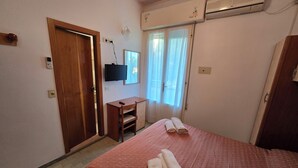 Una camera d'albergo con un letto, una scrivania, una TV e un condizionatore d'aria.