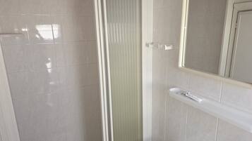 Ein Badezimmer mit Dusche, Toilette und Spiegel.